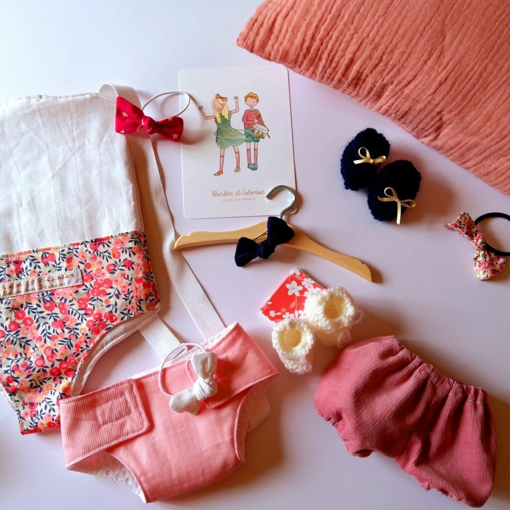 Tout le nécessaire pour s'occuper de sa poupée : porte-poupée, couche, chaussons, bloomer, etc.